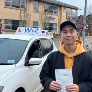 Happy learner holding pass certificate after driving lessons in Manchester with Wiz