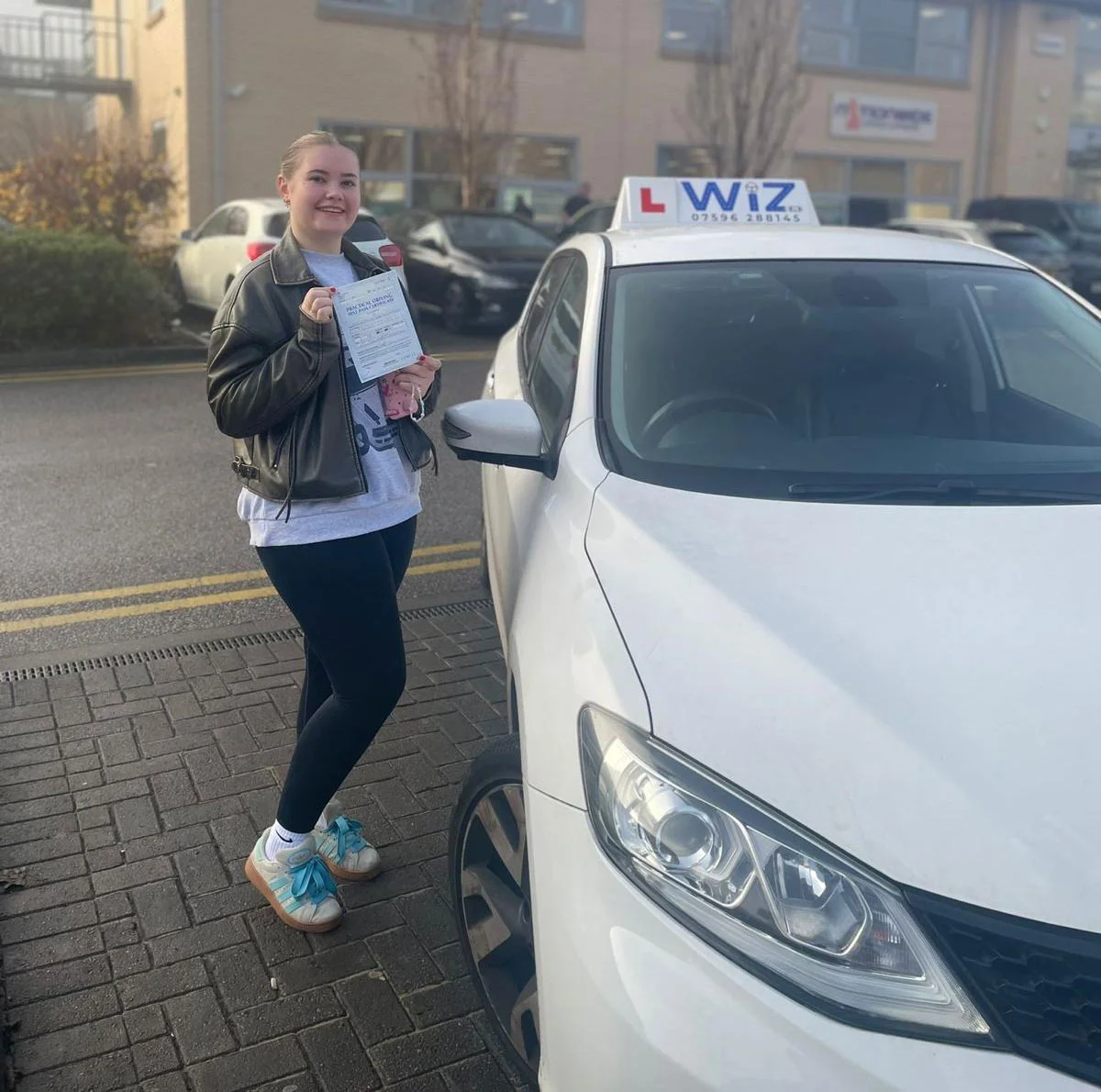 Student stands beside Wiz Driving School branded car in Manchester - DVSA-approved driving lessons